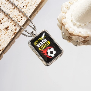 Dettaglio della collana in acciaio con ciondolo da calcio e scritta Set Goals Reach Repeat