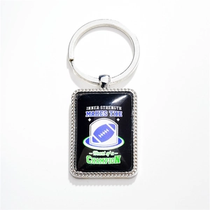 Stainless steel rugby pendant keychain with inner strength champion quote on white background