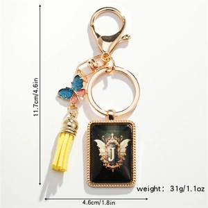 Close-up of golden letter J keychain with blue butterfly charm and yellow silk tassel