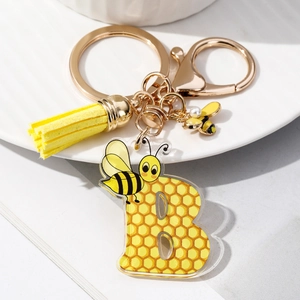 Macro detail of acrylic letter B keychain with yellow honeycomb pattern and bee charms