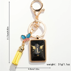 Detailed view of golden keychain with letter L, blue butterfly and yellow tassel