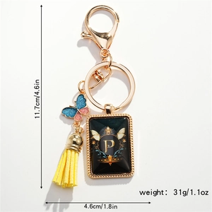 Close-up of golden letter P keychain with butterfly pendant and yellow leather tassel