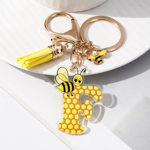 Detailed view of acrylic letter F keychain with honeycomb pattern and yellow tassel