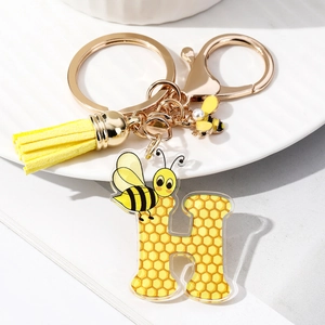 Macro shot of letter H keychain featuring yellow honeycomb pattern and a small bee charm