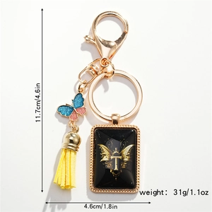 Detail view of golden butterfly keychain with blue-pink charm and letter T pendant