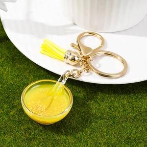 Miniature food bowl keychain featuring yellow porridge with tassel and golden ring