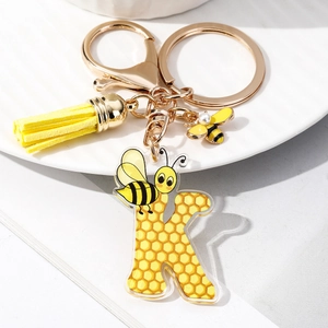 Close-up of letter K keychain with yellow honeycomb pattern and bee tassel charm