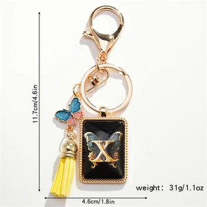 Detailed view of golden butterfly keychain with letter X tag and yellow tassel charm