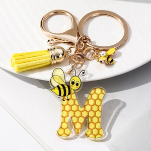 Detail of letter M acrylic keychain featuring honeycomb patterns and yellow tassel