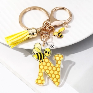 Detail of letter N keychain with acrylic honeycomb pattern, yellow tassel and enamel bee charm