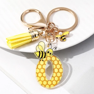 Detail of acrylic letter O keychain with honeycomb pattern and yellow fiber tassel charm