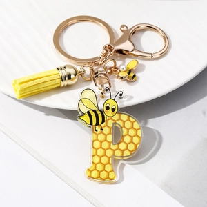 Detail of yellow acrylic letter P keychain with honey bee, honeycomb and silk tassel