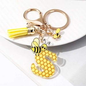 Macro detail of acrylic letter S keychain with honeycomb pattern and yellow leather tassel
