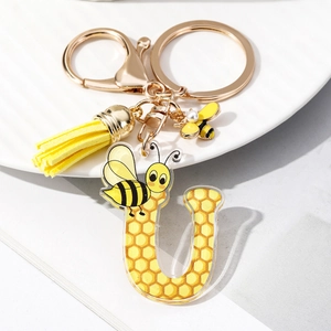 Detail view of acrylic letter U keychain featuring honeycomb pattern and bee charm