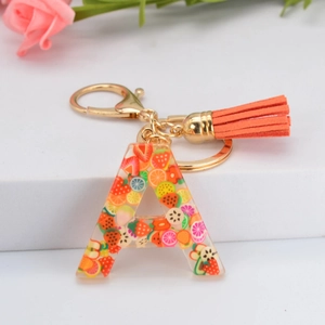 Détail du porte-clés lettre A en résine avec tranches de fruits et pompon orange vif