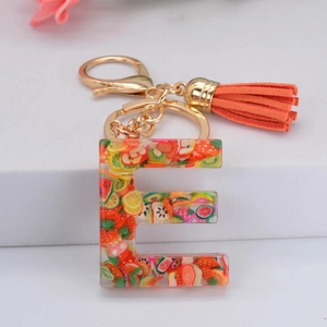 Détail du porte-clés lettre E en résine avec tranches de fruits, fermoir doré et gland orange