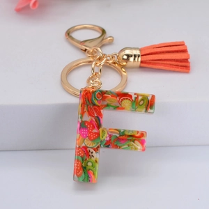 Détail du porte-clés lettre F avec tranches de fruits en résine et pompon orange vif