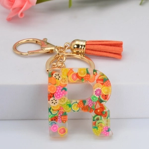 Détail du porte-clés lettre R en résine avec tranches de fruits et pompon orange