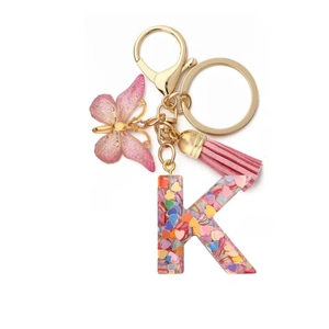 Detail showing resin letter K keychain with pink heart sequins, butterfly charm and tassel