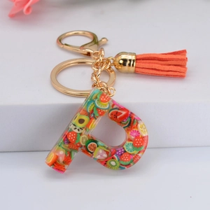 Détail du porte-clés lettre P en résine avec tranches de fruits et pompon orange