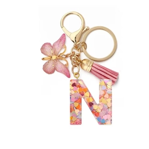 Detail of pink resin letter N keychain with heart sequins and butterfly charm
