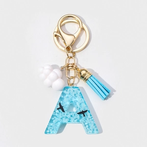 Detail of resin letter A keychain with blue sky clouds pattern and blue tassel charm