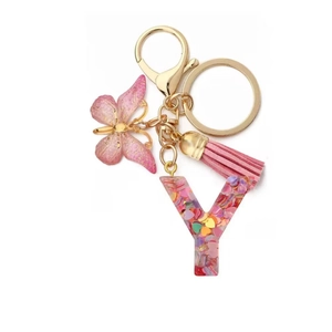 Detail of pink resin letter Y keychain with heart sequins, tassel, and lace butterfly