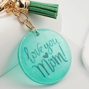 Détail du porte-clés en acrylique pailleté vert menthe avec texte love you Mom et pompon
