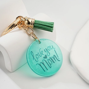 Détail d'un porte-clés en acrylique vert 'Love you Mom' avec un pompon élégant