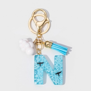 Detail of resin letter N keychain with blue sky clouds pattern and soft blue tassel