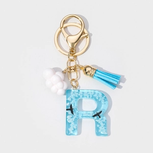 Detailed macro of resin letter R keychain with blue sky clouds and gold lobster clasp