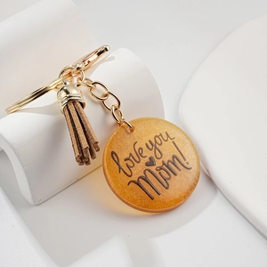 Détail du pendentif en résine ambrée avec gravure Love you Mom et pompon en cuir brun
