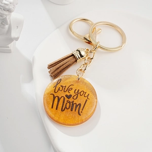 Détail d'un porte-clés en résine ambrée avec gravure Love you Mom et gland marron