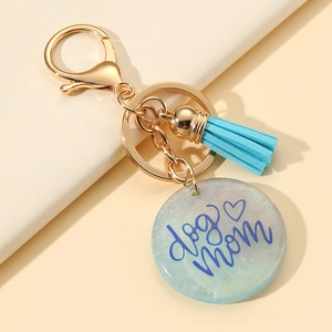Porte-clés doré avec pompon bleu et lettrage dog mom sur un pendentif rond en résine