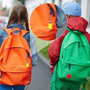 Detail showing acrylic pencil and apple keychains attached to children's school backpacks