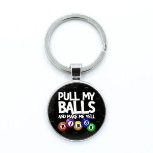 Detail view of round bingo keychain with colorful balls and funny text on black background