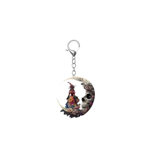 Macro detail of gothic crescent moon keychain with witch, skull and dried roses artwork
