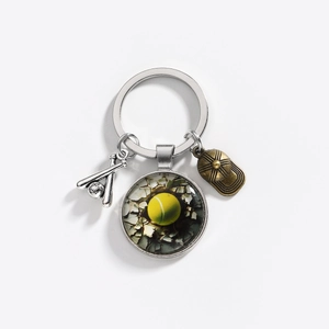 Detailed macro view of tennis ball glass pendant and metal baseball bat key ring