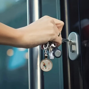 Floral letter M keychain with gold frame shown being used to open a modern door lock
