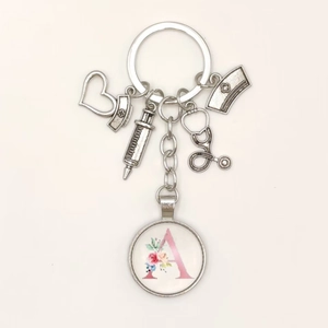 Detail of medical keychain with charms like syringe and floral pink letter A pendant