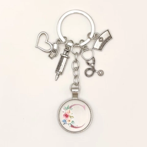Detail of medical keychain with silver charms, nurse hat, syringe and floral letter C