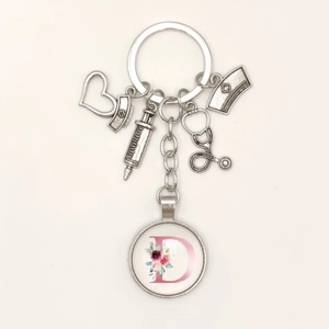 Detailed view of silver medical keychain with stethoscope, syringe and floral letter D charm