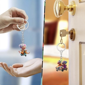 Detail showing cartoon granny on scooter and car acrylic keychain with metal ring