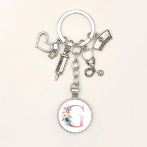 Silver medical themed keychain featuring syringe, stethoscope and floral letter G charm