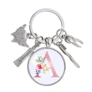 Détail macro du porte-clés dentaire avec breloques argentées et pendentif lettre A