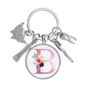 Détail d'un porte-clés dentiste avec brosse à dents, dentifrice et lettre B rose
