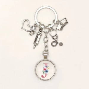 Detail view of silver medical keychain with stethoscope, syringe and floral letter J