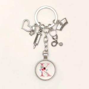 Detail view of silver medical keychain with syringe, stethoscope and floral letter K charms