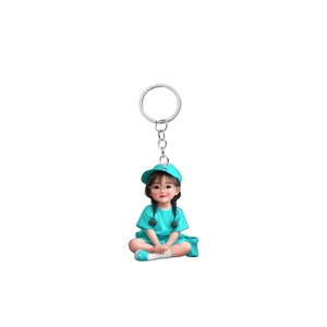Detail of 2D acrylic girl keychain with blue baseball cap and silver metal keyring