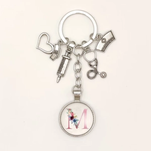 Close-up of nurse keychain charms with medical symbols and pink floral letter M pendant
